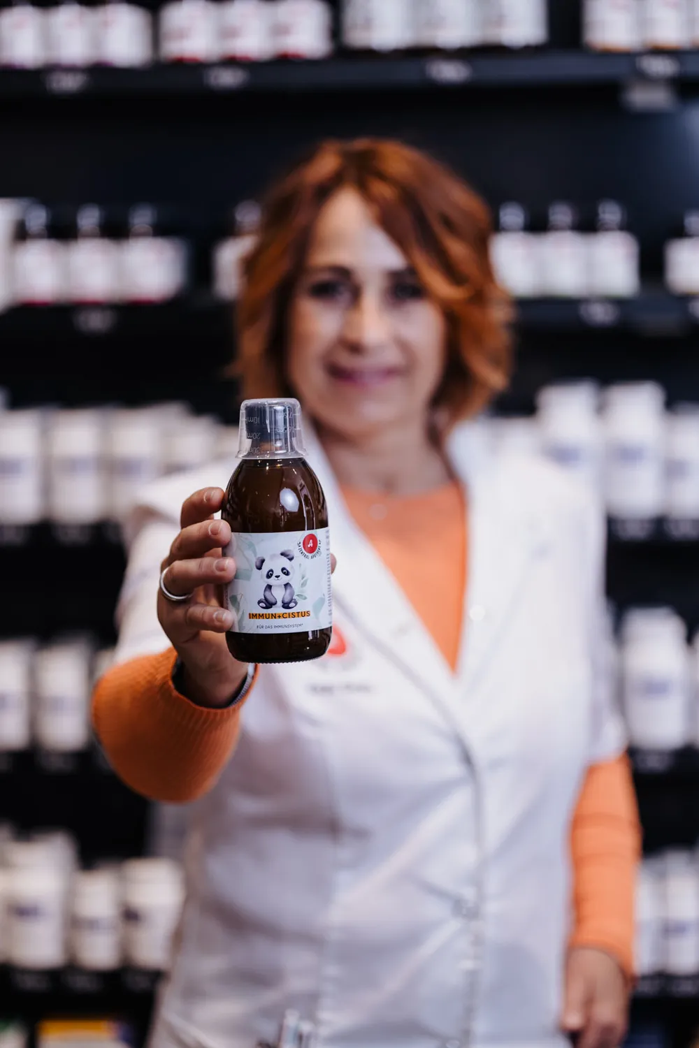 Mitarbeiterin hält eine Flasche Immun + Cistus Kids