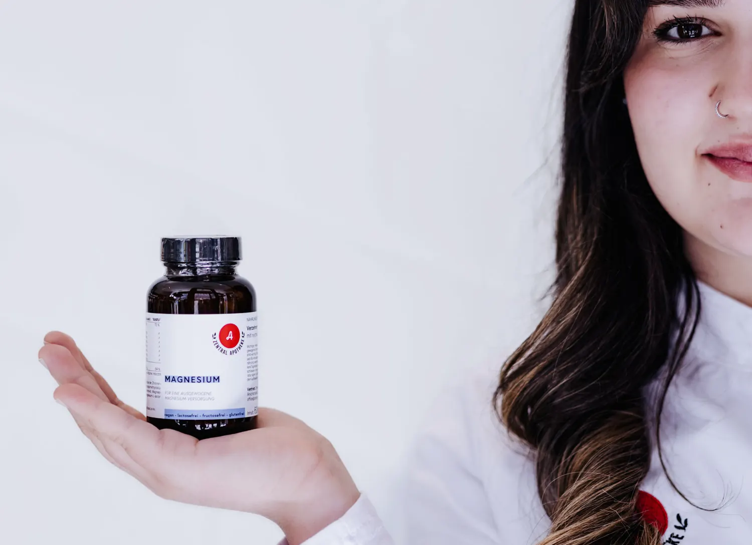 Mitarbeiterin hält eine Dose Magnesium der Eigenmarke mit rotem Apotheken-A auf der Handfläche