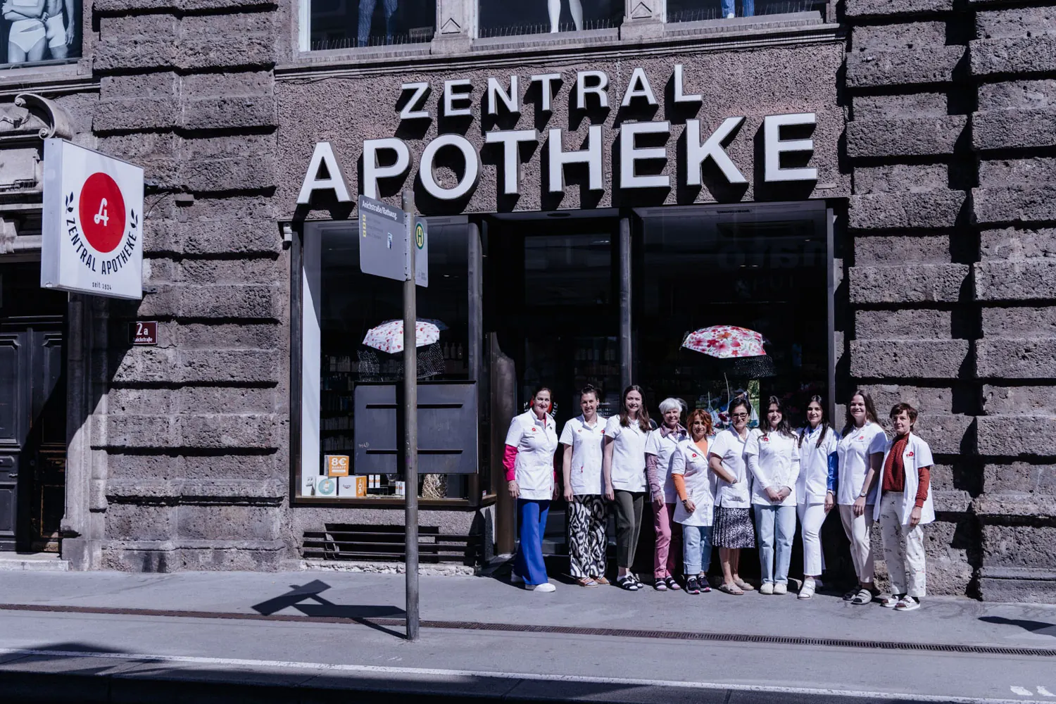 Das Team steht vor der Fassade der Zentral-Apotheke mit dem großen Schriftzug „Zentral Apotheke“ und dem roten Apotheken-A
