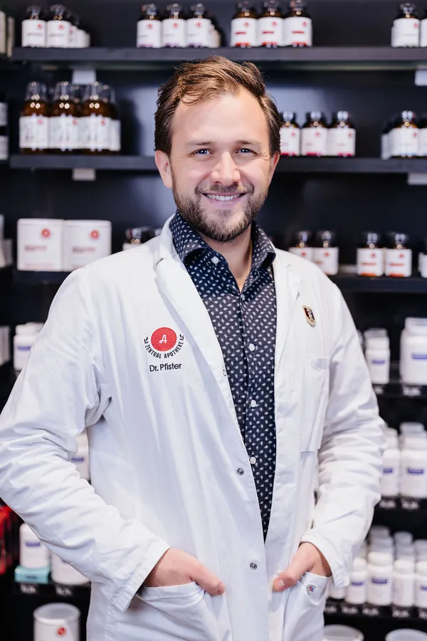 Porträt von Joachim Pfister im weißen Kittel vor dem Apothekenregal