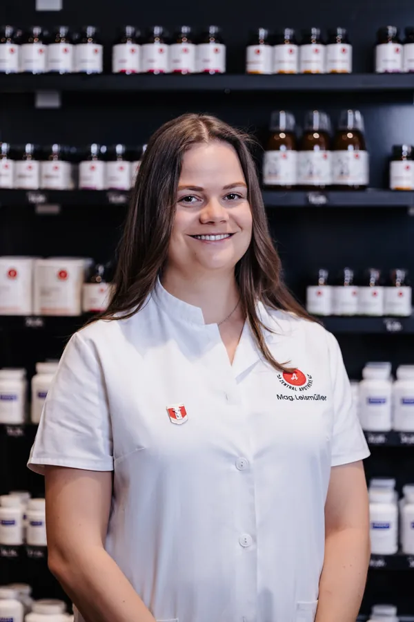 Porträt von Laura Leismüller im weißen Kittel vor dem Apothekenregal