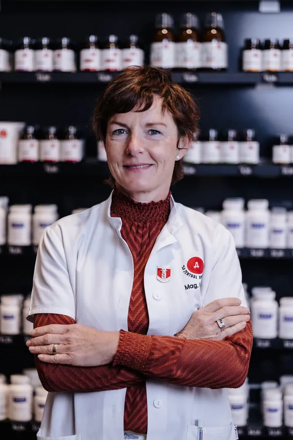Porträt von Nadine Molitor im weißen Kittel vor dem Apothekenregal