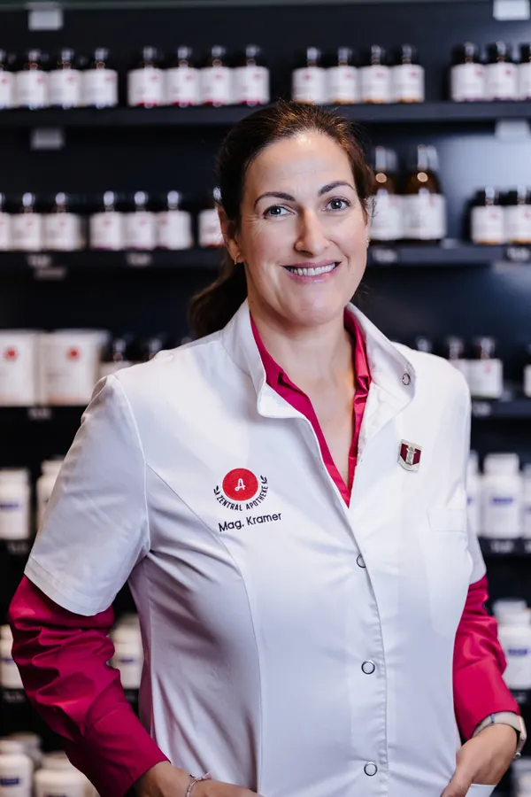Porträt von Sandra Kramer im weißen Kittel vor dem Apothekenregal