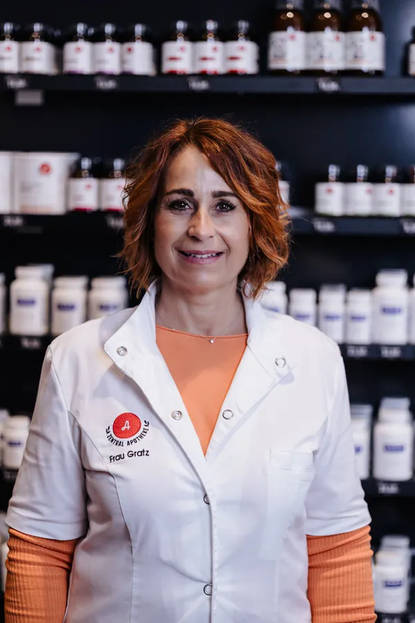 Porträt von Sigrid Gratz im weißen Kittel vor dem Apothekenregal