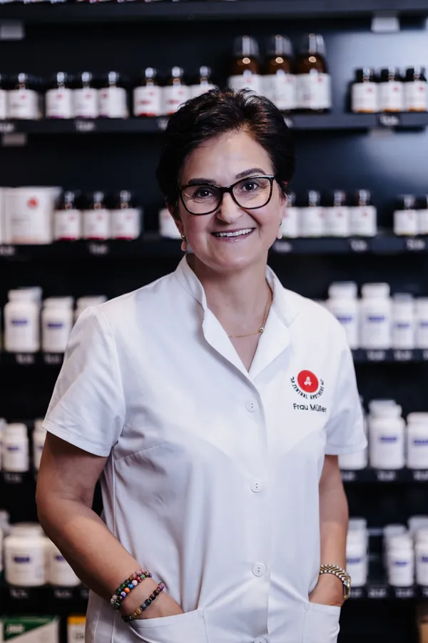 Porträt von Vida Müller im weißen Kittel vor dem Apothekenregal